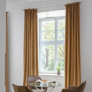 Jadalnia przy wysokim oknie kamienicy ze szklanym stołem i brązowymi krzesłami