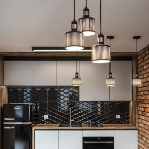 Mała kuchnia z czarną lodówką retro, drewnianym blatem i lampami wiszącymi