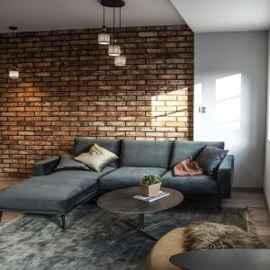 Strefa wypoczynkowa z narożną sofą przy ceglanej ścianie i oknie