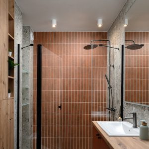 Wąska łazienka z drewnianą zabudową, terakotową ścianą i kabiną walk-in