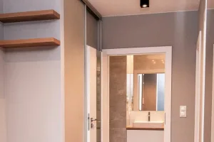 Szafa przesuwna na wymiar w korytarzu z drewnianymi półkami otwartymi – mieszkanie Litomska, MTW Studio Wrocław