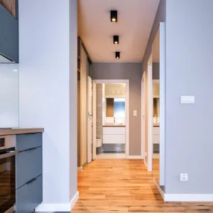 Kompleksowa realizacja mebli na wymiar, widok z kuchni na korytarz z szafą przesuwną i łazienką, mieszkanie 53 m², MTW Studio Wrocław