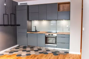 Kuchnia na wymiar z frontami w kolorze antracytu, drewnianym blatem i szklaną ścianą za blatem roboczym – MTW Studio Wrocław